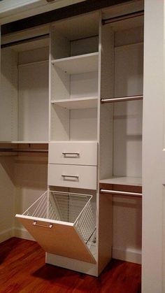 an empty closet is shown with white drawers and shelves on the bottom shelf, along with wooden flooring