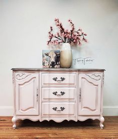 a white dresser with pink flowers on top and a vase sitting on top of it