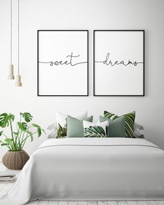 two framed posters above a bed in a white bedroom with green pillows and throw pillows