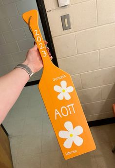 a person holding up a wooden sign with flowers on it that says aoi, today