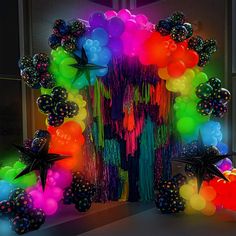 an assortment of balloons and streamers are displayed in front of a doorway at night