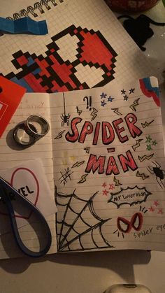 an open notebook with spider man written on it next to some scissors and other items