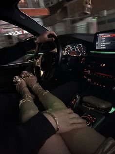 a woman sitting in the driver's seat of a car with her feet on the steering wheel