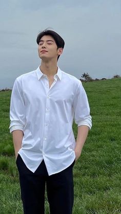 a man standing on top of a lush green field next to a grass covered field