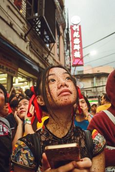 a woman with freckles on her head holding a cell phone in front of a crowd