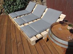 two wine glasses are sitting on top of a wooden pallet that is being used as a lounge chair