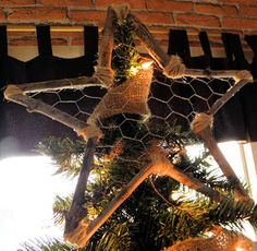 a chicken wire star ornament hanging from a christmas tree with lights on it