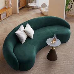 a green curved couch sitting in the middle of a living room next to a coffee table