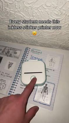 a hand pointing at a notebook with stickers on it and the caption reads, every student needs this inkless sticker printer now