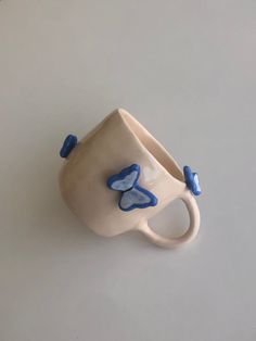 a ceramic cup with blue butterflies on the outside and inside, sitting on a white surface