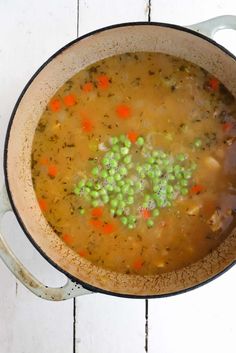 a pot full of soup with peas and carrots