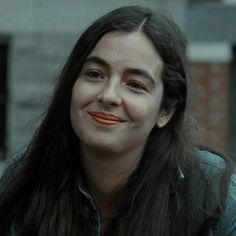 a woman with long dark hair and orange lipstick looks at the camera while she smiles