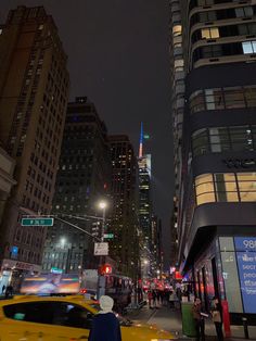 a busy city street at night with cars and people walking on the sidewalk in front of tall buildings