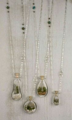 three glass bottles with plants in them hanging from chains