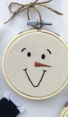 a close up of a small embroidered face on a piece of cloth with scissors and thread