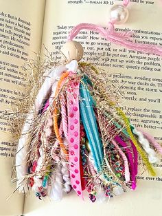 an open book with several different colored hair ties on it's cover and some beads hanging from the top