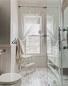 a white toilet sitting next to a window in a bathroom near a shower stall and sink