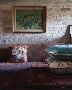 pillows are stacked on top of each other in front of a wall with a painting