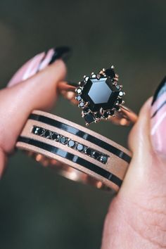 a woman's hand holding two rings with black and white designs on the sides