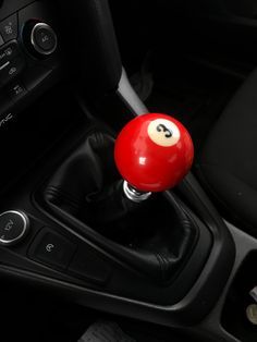 a red ball with a number 8 on it sitting in the center console of a car