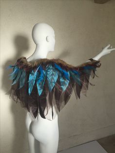 a white mannequin with blue and brown feathers on it