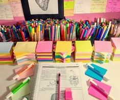 many different colored pens are on top of a book and some books with sticky notes attached to them