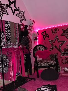 a room filled with zebra print clothes and pink lights on the walls, along with black and white bedding