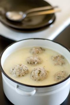 a white pot filled with meatballs and broth