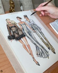 a drawing of two women's dresses with feathers on the front and back, being drawn by a person holding a pencil