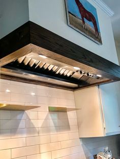 a stove top oven sitting inside of a kitchen next to a painting on the wall