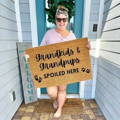 a woman holding up a sign that says grandmas and grandpas spoiled here on the front porch