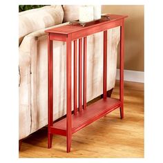 a red end table sitting on top of a wooden floor next to a white couch