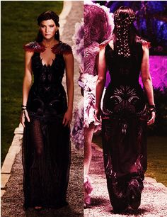 two models walking down the runway in black and purple dresses with feathers on their shoulders