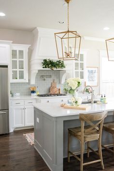 a kitchen with white cabinets and an island in the middle, surrounded by stools