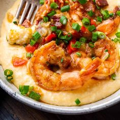 a plate with shrimp and grits topped with scallions, green onions, and bacon