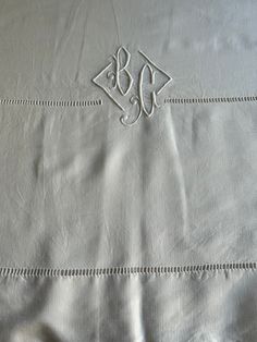 an embroidered monogrammed bed sheet with the initials b and c