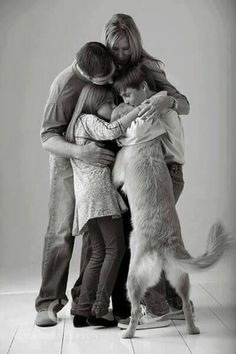 black and white photograph of three people hugging a dog