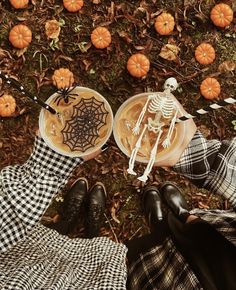 two people are sitting on the ground with pumpkins and skeletons in their hands,