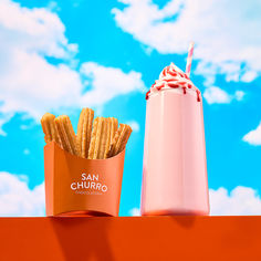 a pink cup with a straw and some fries in it sitting on top of a table