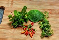 some vegetables are laying on a wooden cutting board with a knife and sprigs