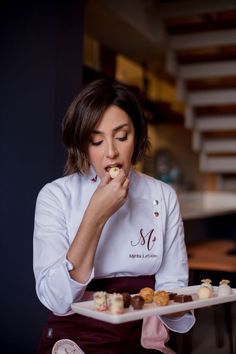 a woman in white shirt and apron eating food