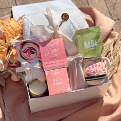 an assortment of bath products in a box on a table with pink and white cloth