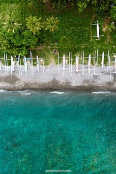 an aerial view of the ocean and beach with white umbrellas on poles sticking out of the water