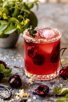 a red cocktail with cherries on the rim