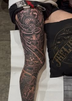 a person with tattoos on their legs sitting next to a pillow