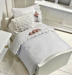 a white bed with pink flowers on it and two pillows in front of the headboard