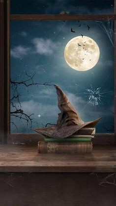 an open book sitting on top of a wooden table under a full moon filled sky