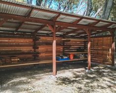 a wooden shelter with benches and trash cans