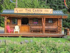 the cabin is made out of wood and has two chairs on it's porch