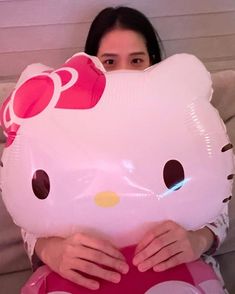 a woman is holding a large hello kitty balloon